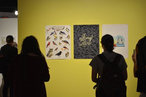 Visitors viewing bird species poster and Jenny Lewis artwork on bright yellow museum wall