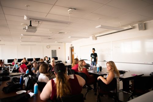 Students in modern classroom with computers and whiteboard during interactive learning session