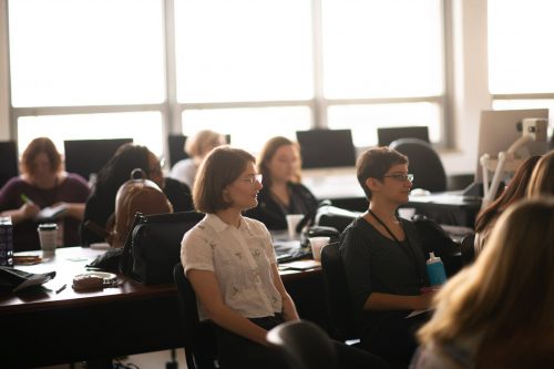 Professional women attending business meeting or workshop in modern conference room with large windows