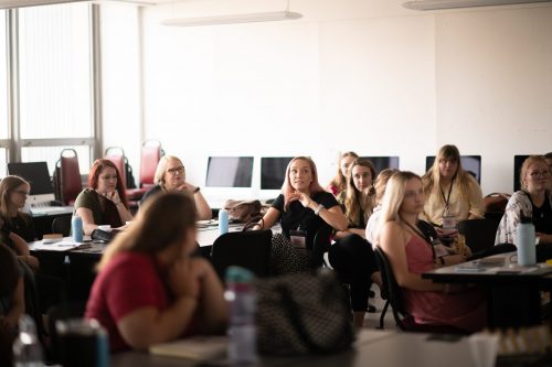 Women attending professional development seminar in modern conference room with laptops and natural lighting