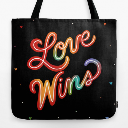 Black tote bag with rainbow Love Wins text in cursive script and colorful hearts scattered on dark background