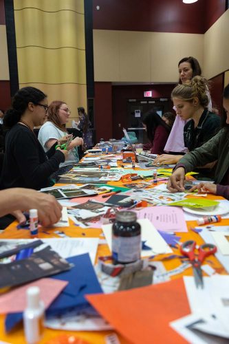 Students creating colorful art projects with paper, photos and craft supplies during collaborative workshop session
