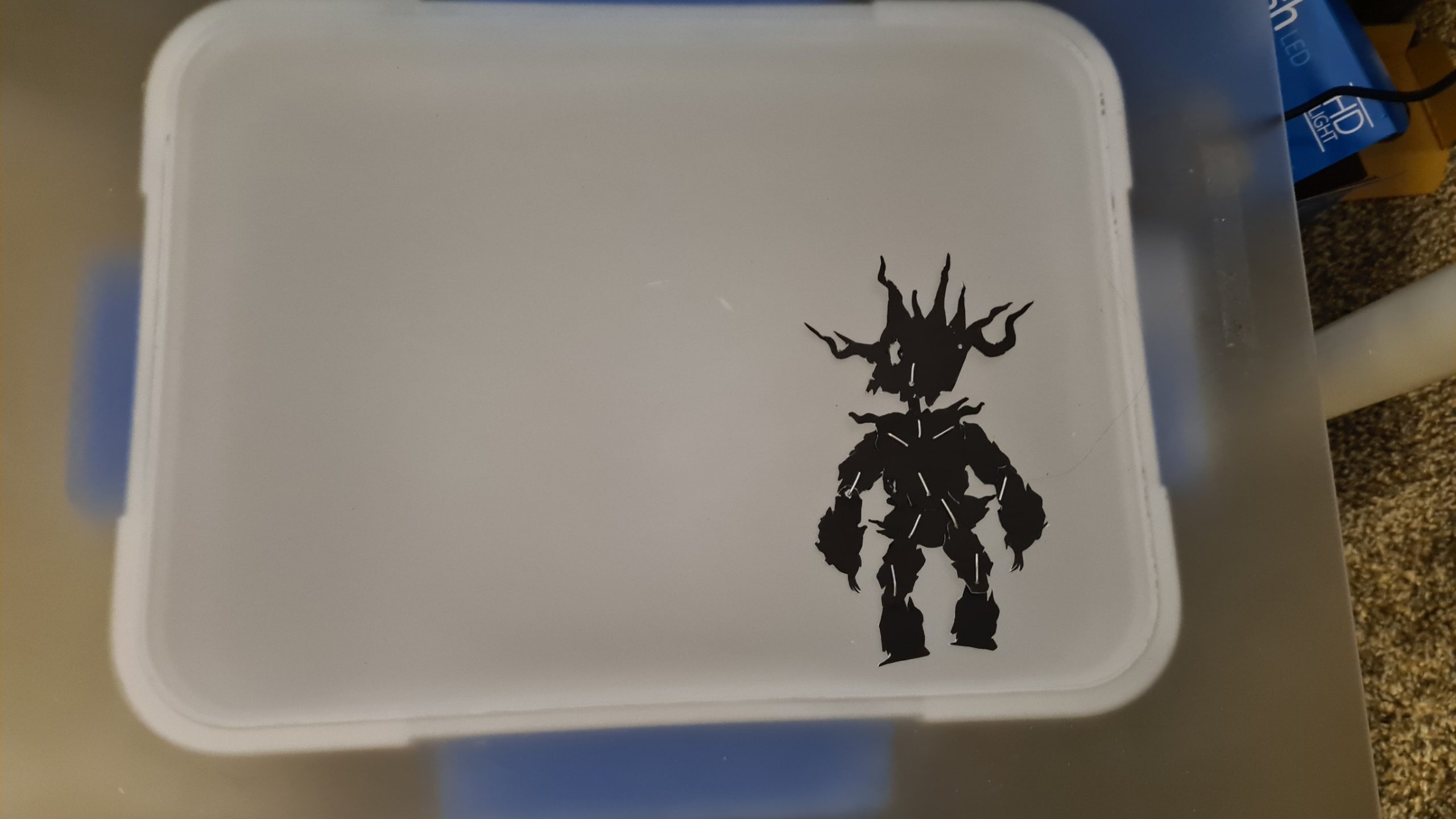 White storage container with black silhouette decal of armored fantasy warrior character with spikes and horns